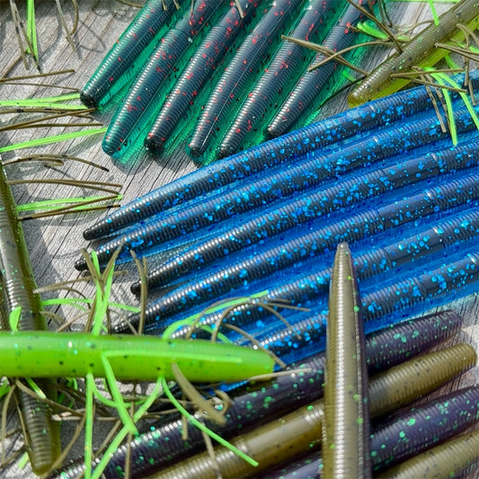 Big League Bait Company Boombox this kit is pictured with several soft plastic fishing lures. All of the soft plastic baits are variations of Big League Bait Company's Boomstick. A senko style stick worm with Wacky Rig O-rings, Eagle Claw EWG 4/0 Hooks and Wacky Rig hooks. Shown in 4 colors. BoomBox includes the Standard Boomstick, Corked Boomstick (Core Shot Stick Worm) and Skirted Boomstick (Fuzzy Senko style bait)