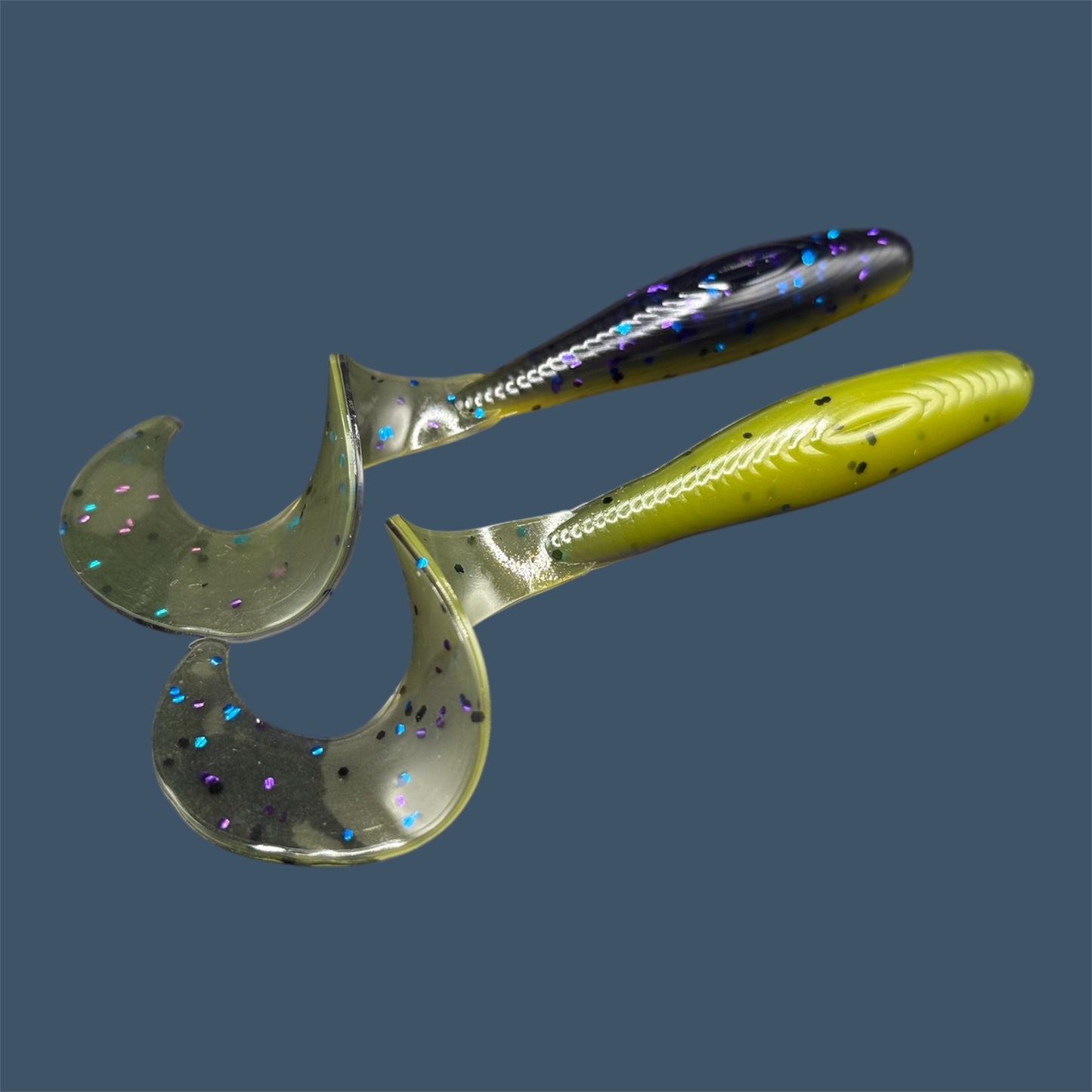 Single Tail Grub with a thick curl tail for strong water displacement, shown in Luau a proven fish-catching color suitable for both freshwater fishing and inshore saltwater fishing. (Purple over Banana Seed)