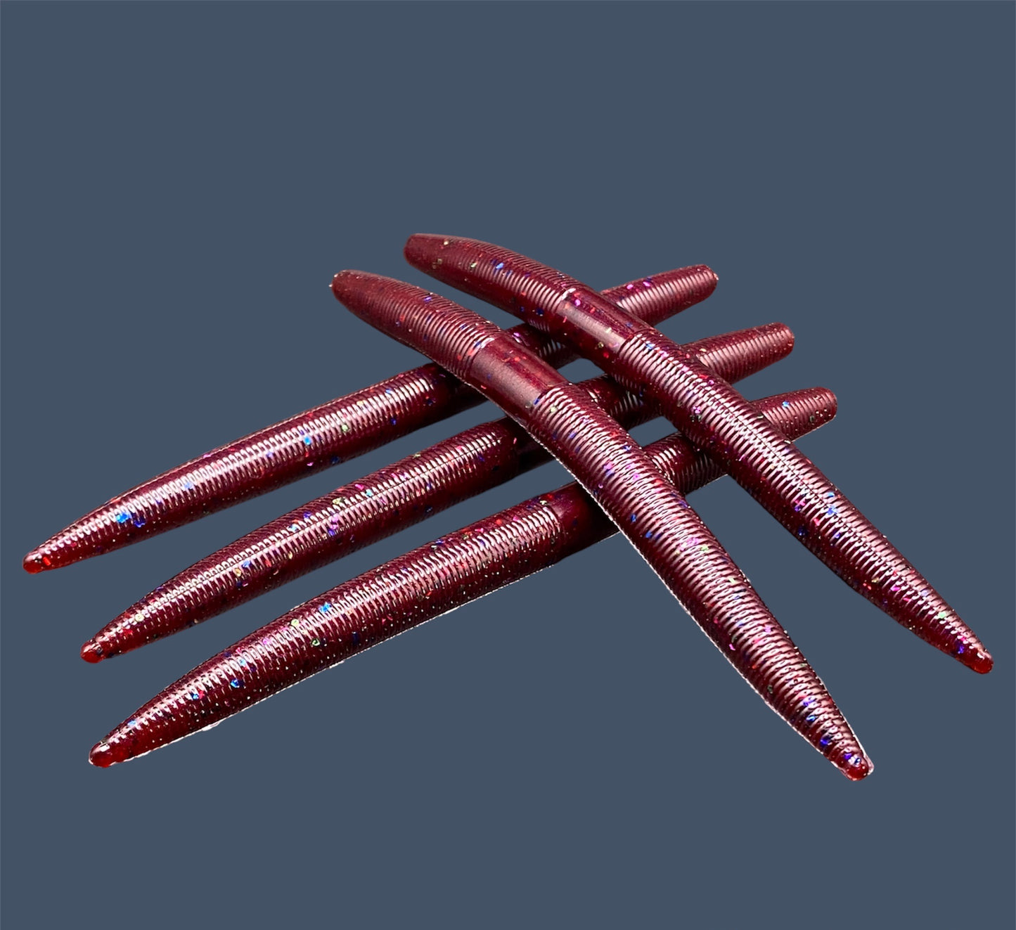 Boomstick is a senko-style stickbait for flipping, skipping, and casting, displayed in Plum Silly (Red) for different fishing conditions in freshwater fishing. Great addition to any anglers tackle box
