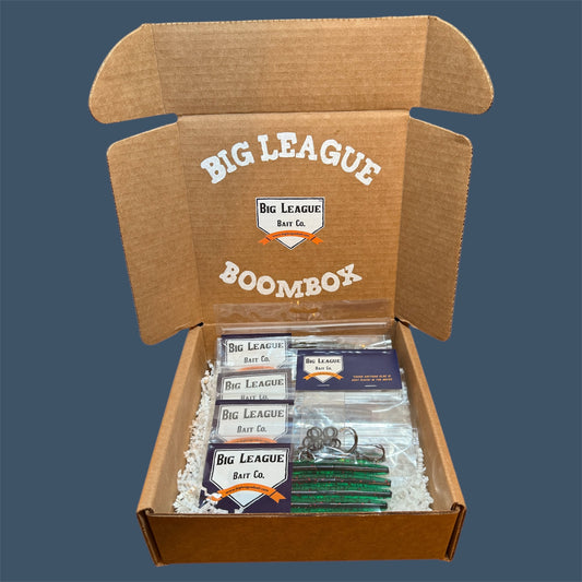 Big League Bait Company Boombox this kit is pictured with several bags of soft plastic fishing lures. All of the soft plastic baits are Big League Bait Company's Boomstick. A senko style stick bait with Wacky Rig O-rings, Eagle Claw EWG 4/0 Hooks and Wacky Rig hooks. 