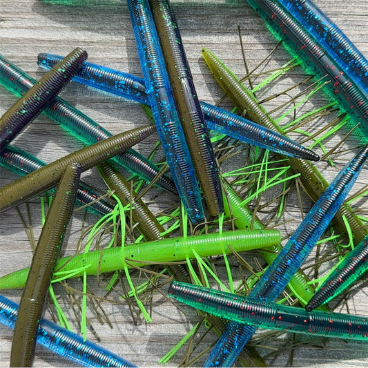 Big League Bait Company Boombox this kit is pictured with several soft plastic fishing lures. All of the soft plastic baits are variations of Big League Bait Company's Boomstick. A senko style stick worm with Wacky Rig O-rings, Eagle Claw EWG 4/0 Hooks and Wacky Rig hooks. Shown in 4 colors. BoomBox includes the Standard Boomstick, Corked Boomstick (Core Shot Stick Worm) and Skirted Boomstick (Fuzzy Senko style bait)